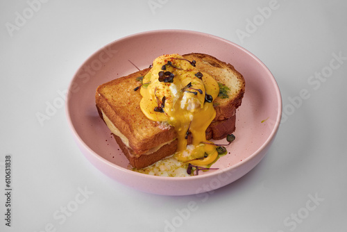 Classic Croque Madame with poached egg and ham in a bowl on a gray background