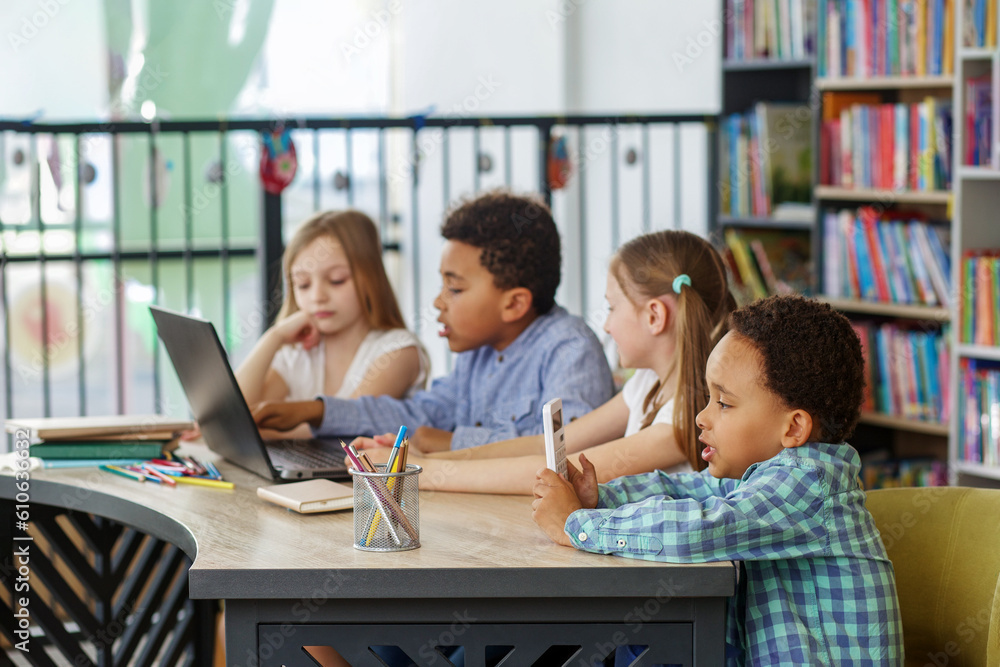 Multiracial group of children sitting in row at school classroom and using laptops. Back to school. Multiracial group of children sitting in row at school classroom and using laptops. Back to school.
