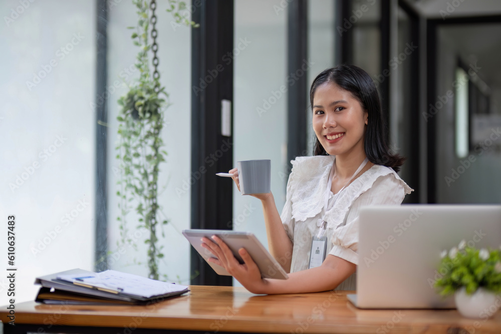 Beautiful young Asian businesswoman drinking a coffee working on laptop at office. Beautiful young Asian businesswoman drinking a coffee working on laptop at office.