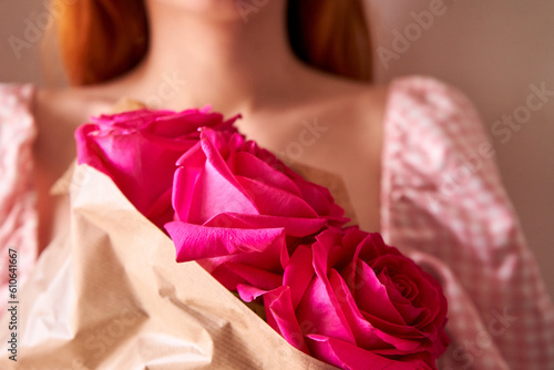 Close up  woman hands holding bouquet of bright pink roses flowers. Front view. Valentine's, women's, mother's day or birthday gift.Beautiful bright bouquet of  flower buds in hands of young woman.