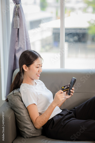 beautiful woman with happiness Hold your credit card and smart phone while at the top on the couch at home. © Witoon