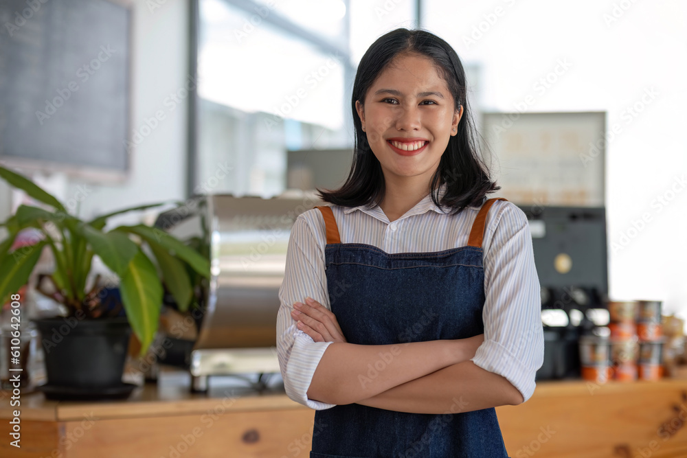 A beautiful and friendly young Asian female waitress in an apron stands in front of the coffee shop counter with her digital tablet. Hospitality service, business entrepreneur, small business startup A beautiful and friendly young Asian female waitress in an apron stands in front of the coffee shop counter with her digital tablet. Hospitality service, business entrepreneur, small business startup