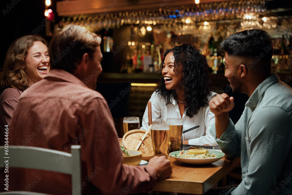 Young multiracial group of friends in casual clothing laughing around table with food and drinks