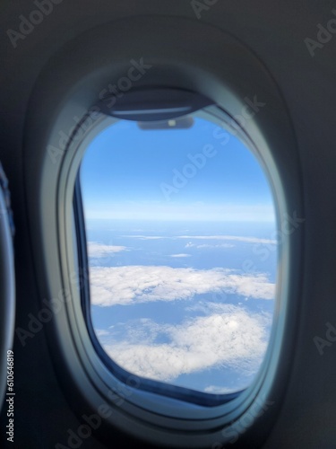 View from the airplane window on the clouds and blue sky through the porthole