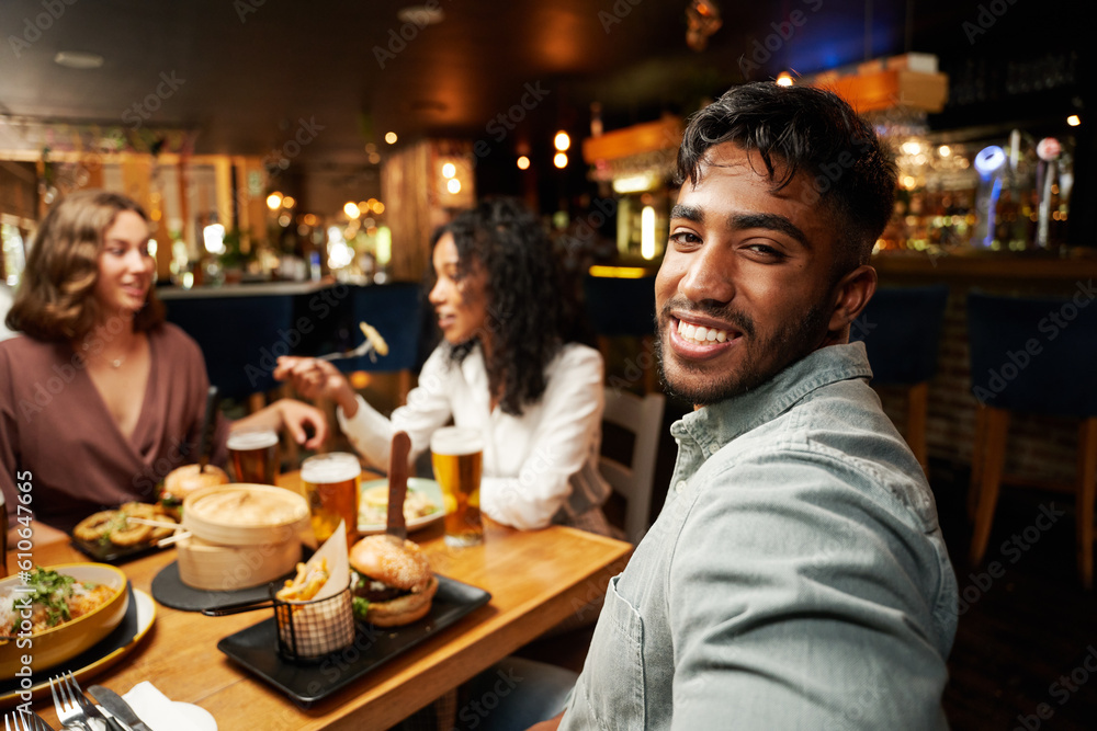 Happy young multiracial group of friends in casual clothing eating dinner at restaurant