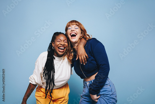 Two interracial best friends laughing and having a good time together in a studio photo