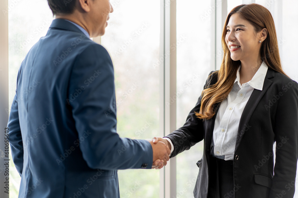 Businessman and businesswoman shaking hand for partnership agreement contract success deal at business meeting. Asian businesspeople handshake greeting client manager partner in corporate office.