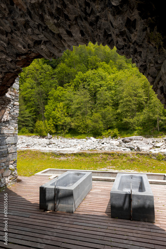 Thermal bath tubs with a view of the river and Swiss nature. View from inside a cave photo