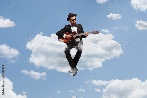 Man playing an acoustic guitar and sitting on a cloud