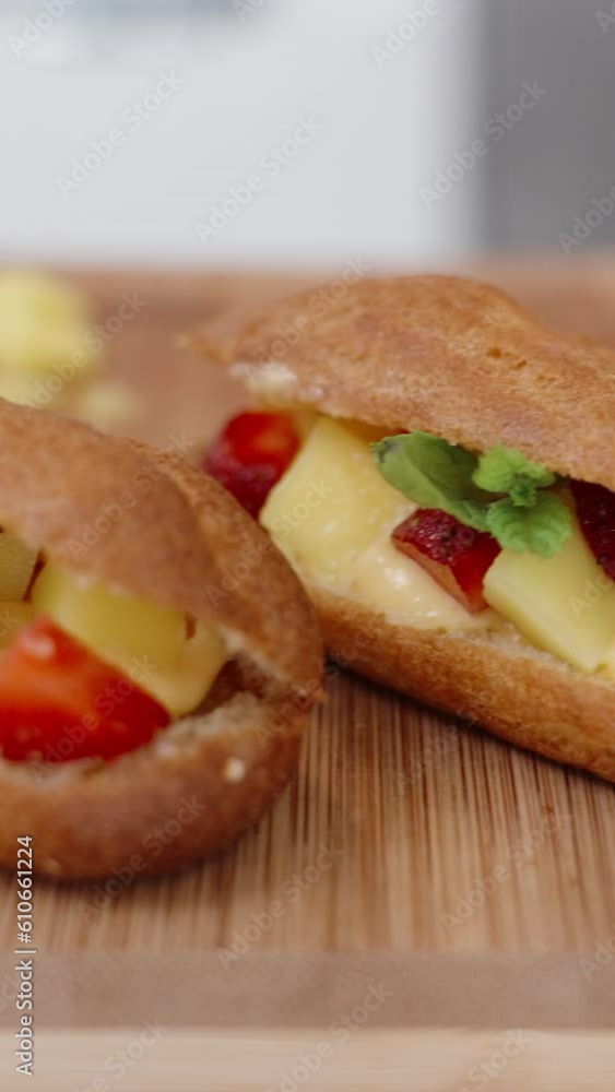 Eclair pastries with strawberry filling and garnished with mint. They are presented on a wooden table in close-up. Vertical video. Eclair pastries with strawberry filling and garnished with mint. They are presented on a wooden table in close-up. Vertical video.