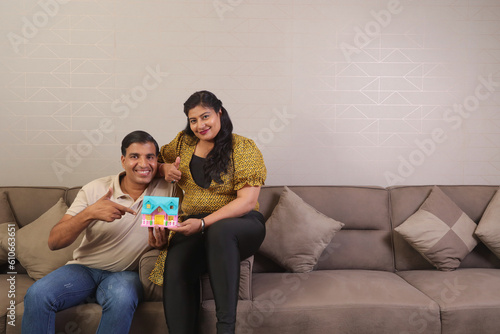 Indian happy Couple eating salad and healthy diet sitting on a sofa holding a laptop surfing online. photo