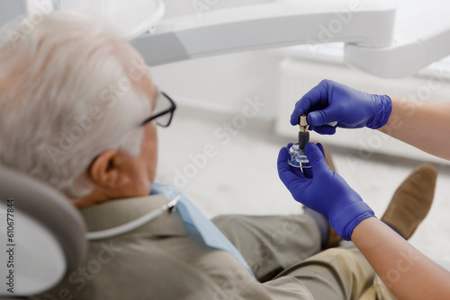 At dental clinic patient old man sitting on the dentist chair the doctor treating cavities with special dental instruments doctor working very professional