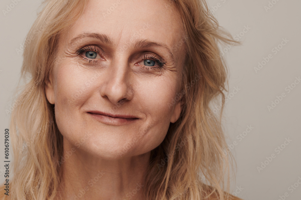 Beautiful blond middle aged woman smiling face looking camera portrait