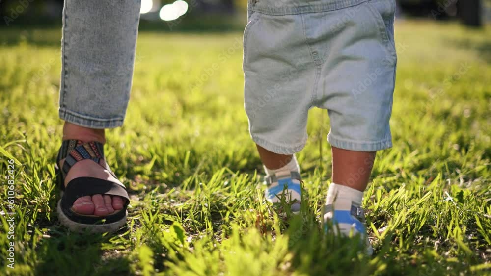 Happy family. Baby takes first steps with his parents.First steps on picnic in park on green grass,baby plays with his mother and father.Fun in summer in park on grass.First steps in spring happy days Happy family. Baby takes first steps with his parents.First steps on picnic in park on green grass,baby plays with his mother and father.Fun in summer in park on grass.First steps in spring happy days