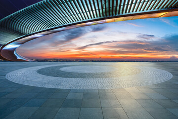 Empty square floor and bridge with city skyline at sunset