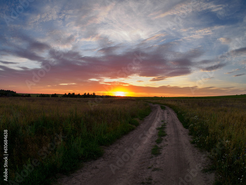 Sunset in the field, dirt road. colorful sky