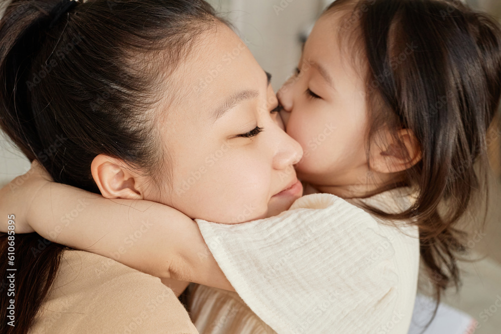 Asian little girl embracing and kissing her mom Asian little girl embracing and kissing her mom