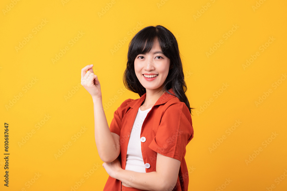 Portrait young beautiful asian woman happy smile dressed in orange clothes showing thinking gesture isolated on yellow studio background. Portrait young beautiful asian woman happy smile dressed in orange clothes showing thinking gesture isolated on yellow studio background.