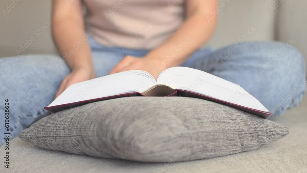 A girl in jeans reads a book on the sofa. A girl in jeans reads a book on the sofa.