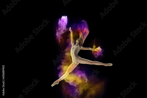 Artistic, talented young girl, ballet dancer in beige bodysuit performing with colorful explosion of powder over black studio background. Concept of art, festival, beauty of dance, inspiration, youth