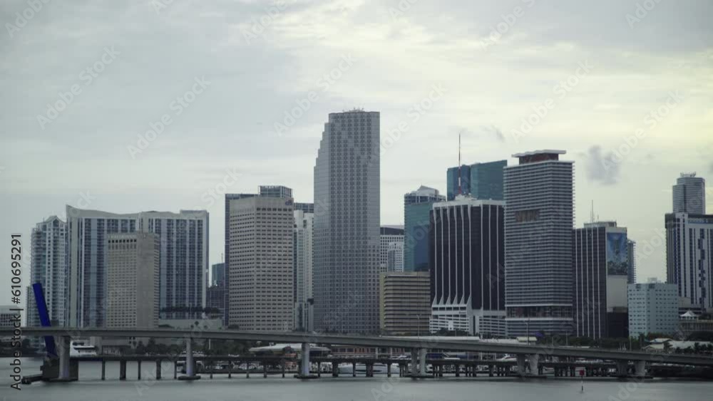 Lockdown Time Lapse Shot Of Bridge Over Sea Near Modern Buildings In City Against Cloudy Sky At Dusk - Miami, Florida Lockdown Time Lapse Shot Of Bridge Over Sea Near Modern Buildings In City Against Cloudy Sky At Dusk - Miami, Florida