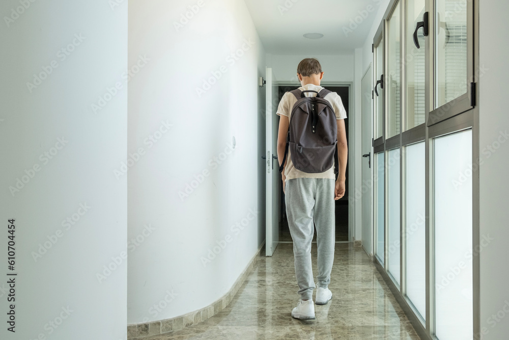 Sad frustrated teenage boy walks away down school corridor alone. Education difficulties, problem with family, emotion, anxiety, depression in adolescence concept Sad frustrated teenage boy walks away down school corridor alone. Education difficulties, problem with family, emotion, anxiety, depression in adolescence concept