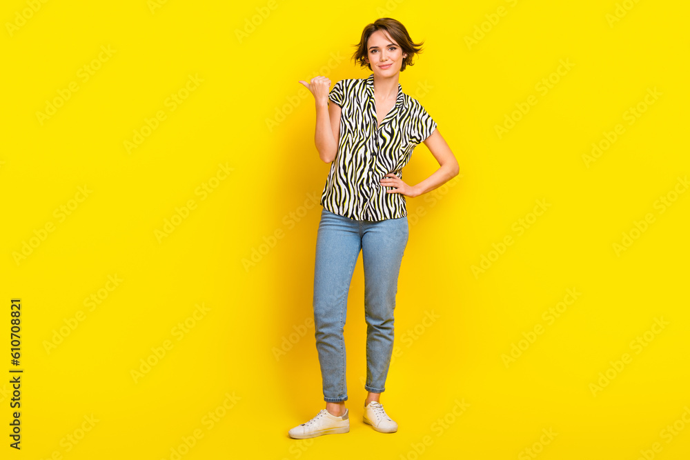 Full size photo of business lady direct thumb finger empty space wear print blouse jeans shoes isolated yellow color background Full size photo of business lady direct thumb finger empty space wear print blouse jeans shoes isolated yellow color background