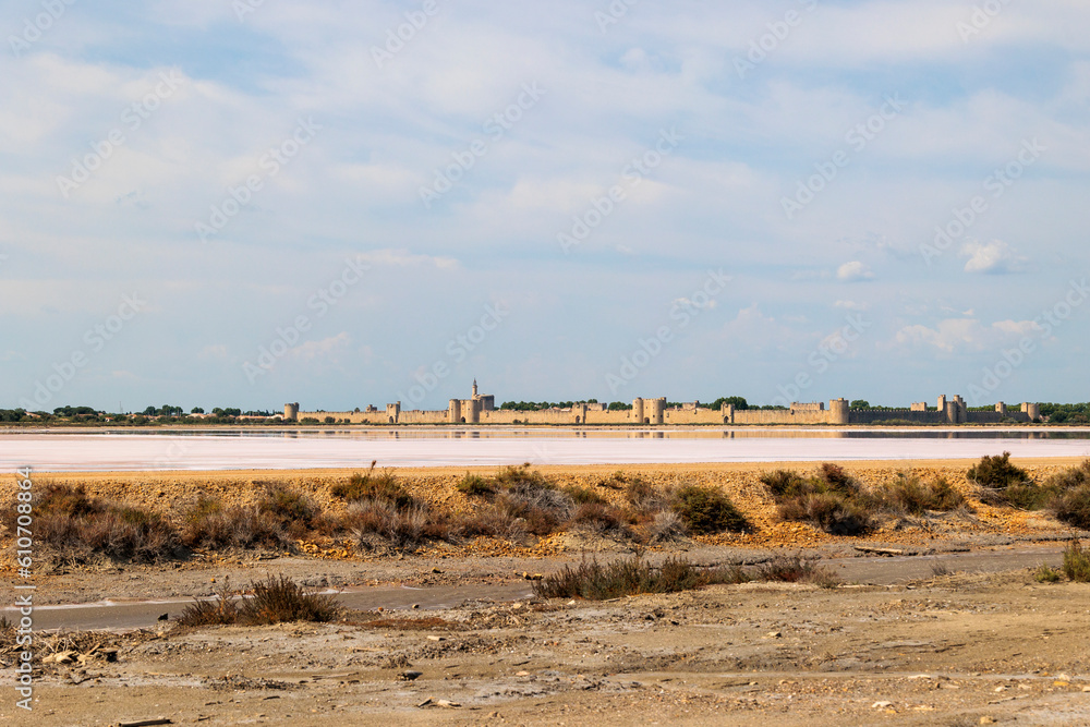 View over the pink salt pans of salt production to the town of Aigues-Mortes in the Camarque region of France View over the pink salt pans of salt production to the town of Aigues-Mortes in the Camarque region of France