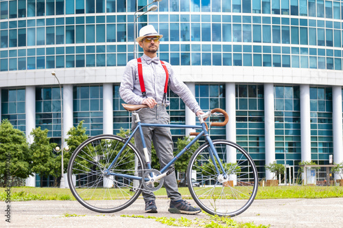 Fototapeta Naklejka Na Ścianę i Meble -  Adult hipster man with retro fixed gear bicycle on modern skyscraper background