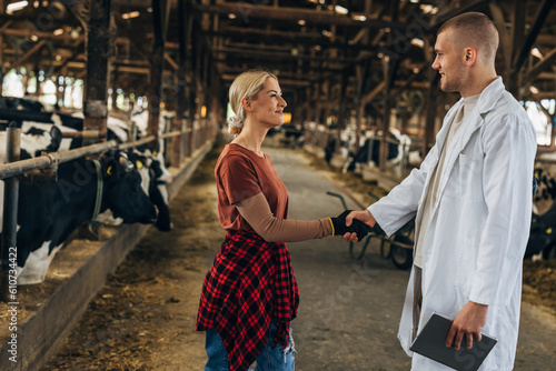 Grateful woman shakes veterinarians hand in a stable.