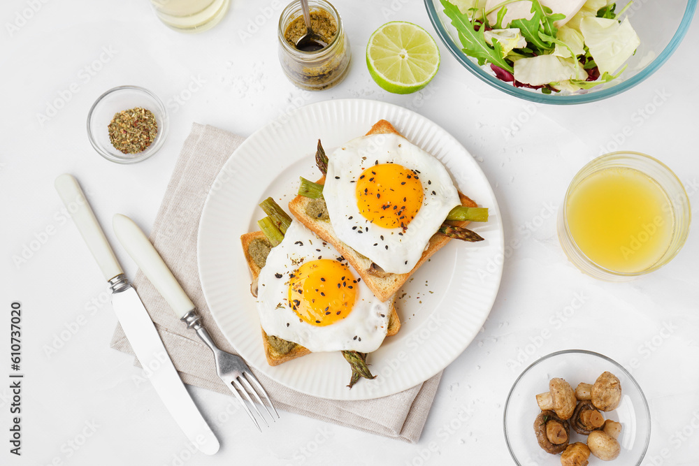 Delicious sandwiches with fried eggs and asparagus on light background Delicious sandwiches with fried eggs and asparagus on light background