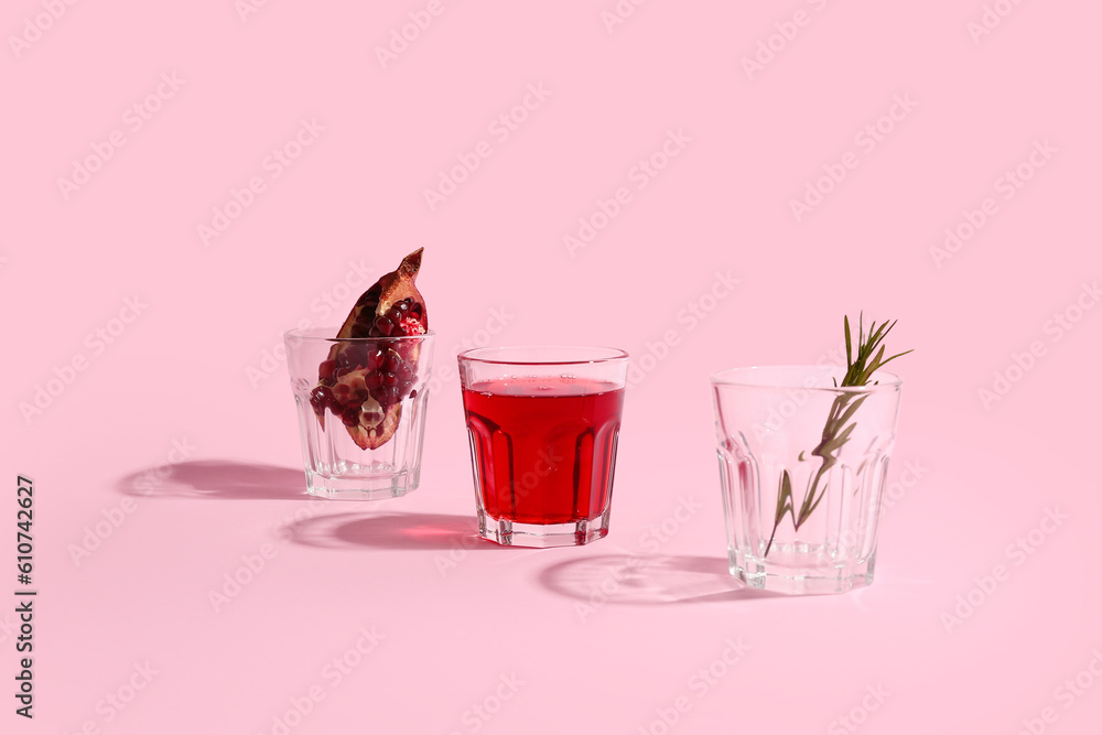 Glasses of fresh pomegranate juice and rosemary on pink background Glasses of fresh pomegranate juice and rosemary on pink background