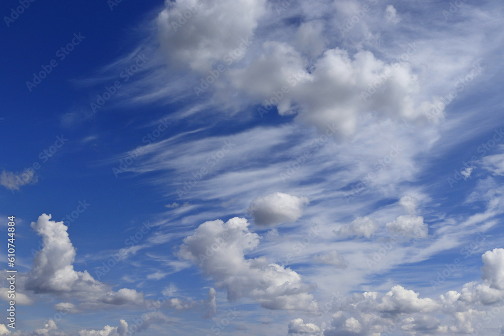 Fototapeta premium An image of a summer blue sky with a beautiful pattern of white clouds of various shapes.