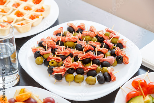 caviar and canape with olives and cheese ham on white buffet tables.