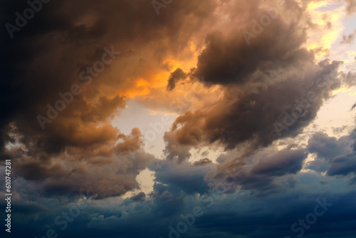 Stormy sky with clouds with blue and yellow hues and clear sky in the center
