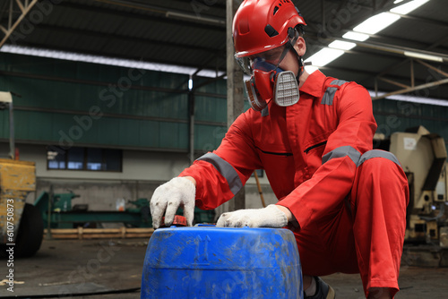 Worker maintenance or scientist industry wearing protective safety uniform, white glove and gas mask to work about open the cap of gallon of lubricant .