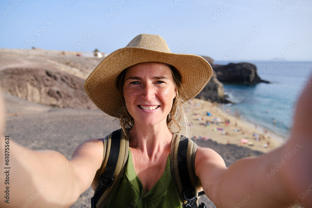 Female tourist making selfie photo with Papagayo beach on the background on Lanzarote island
