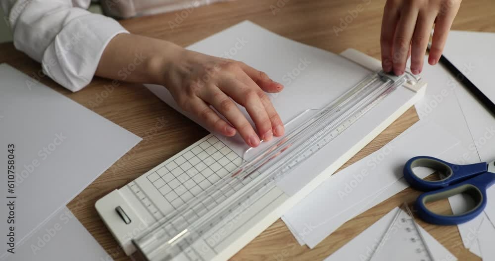 Person uses manual paper cutting device at office desk. Stationery and paper cutting Person uses manual paper cutting device at office desk. Stationery and paper cutting