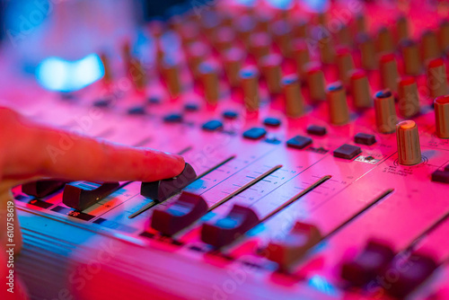 professional recording studio sound engineer finger adjusts sound volume level on mixer console equalizer music creation neon light