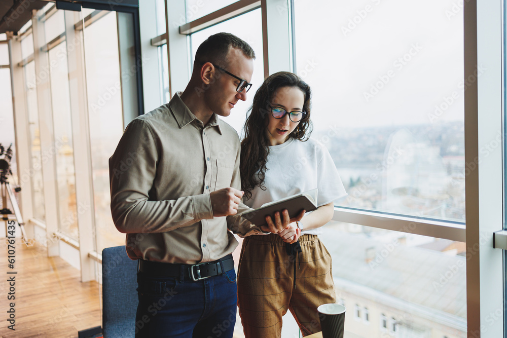 Young male and female colleagues work in a spacious office. Successful people are working on a new business project. Collective work in the office