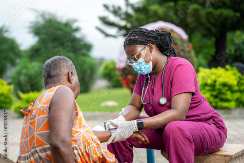 Obraz na plátně image of african young nurse in facemask, diagnosing senior woman outside- homec