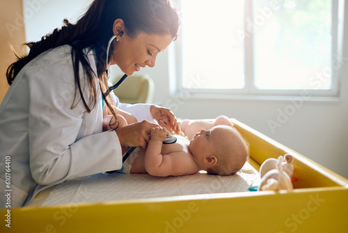 Female doctor listens baby's heart with stethoscope during regular medical checkup at pediatric clinic. photo