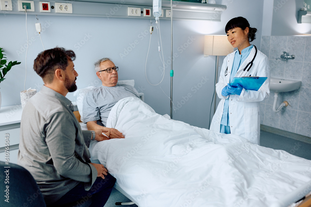Obraz premium Female doctor talk to senior patient and his son in hospital.