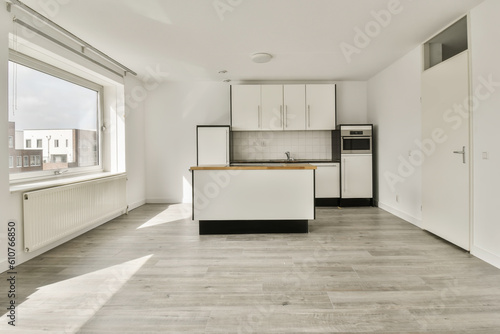 an empty kitchen and dining area in a house with white walls  wood flooring and large windows looking out onto the street