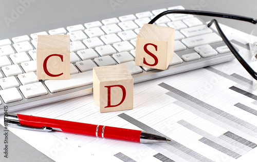 CDS written on a wooden cube on the keyboard with chart on grey background