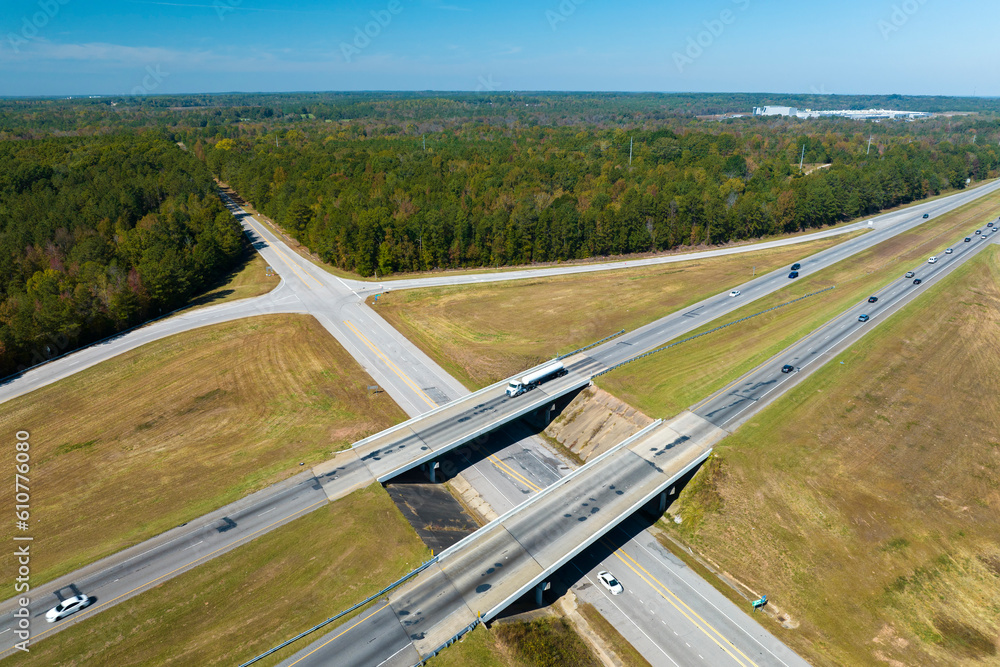 Aerial view of freeway overpass junction with fast moving traffic cars and trucks in american rural area. Interstate transportation infrastructure in USA