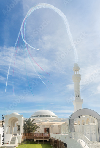 Jets stunts with smoke traces over white Alrahmah mosque, Jeddah, Saudi Arabia photo