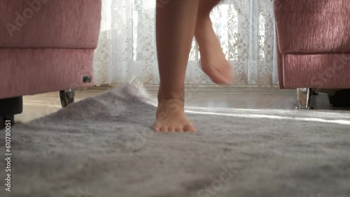 Female stumble in the room. A view of young girl bare legs stumbles upon the carpet in the room.