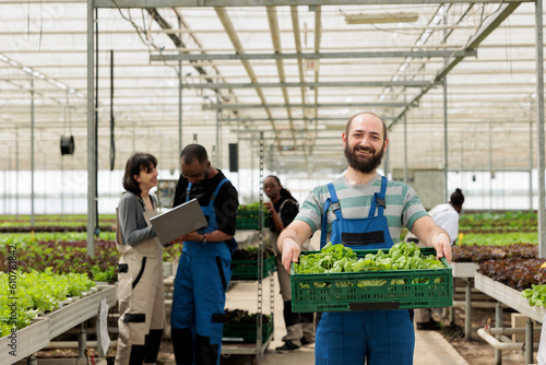 Fotografija Busy group of farmers in modern entrepreneurial bio agricultural greenhouse used for growing natural healthy eco vegetables