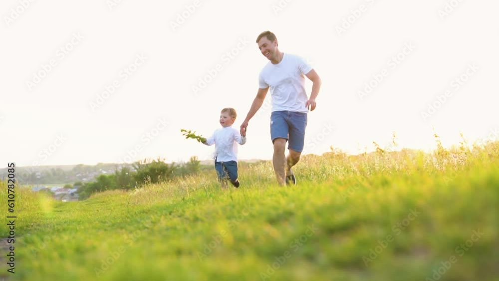 Happy father and little son run together in sun in park. Happy family team. Family game. Father and child son fun run Happy father and little son run together in sun in park. Happy family team. Family game. Father and child son fun run